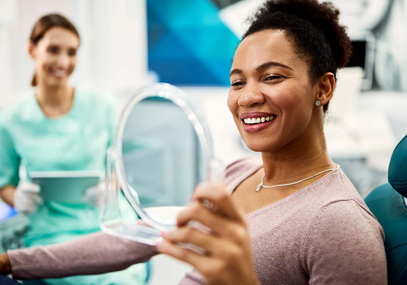 Woman checking smile in small handheld mirror