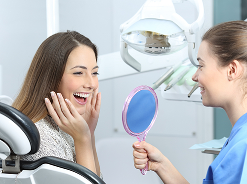 Dentist showing patient smile in handheld mirror