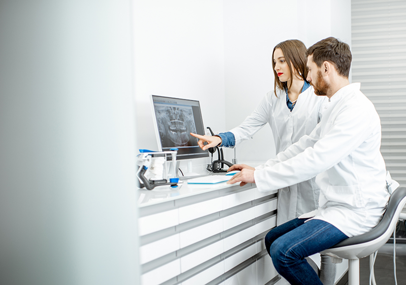 Male and female dentist looking at a dental X ray