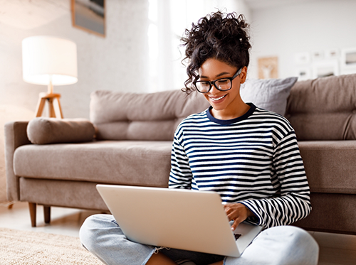 Woman sitting in front of couch and working on laptop