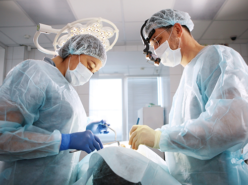 Patient being treated by two dentists with face masks