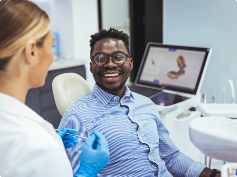 Man in button up shirt laughing in dental chair