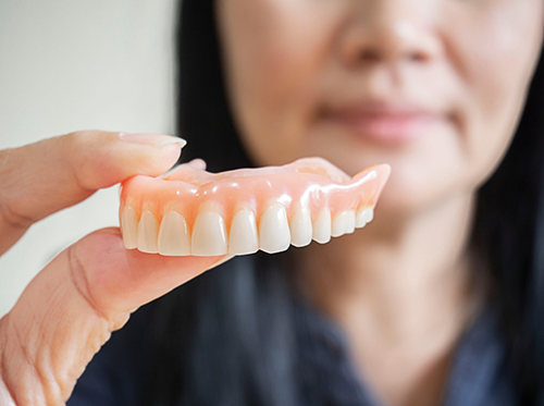 Close up of woman holding a denture